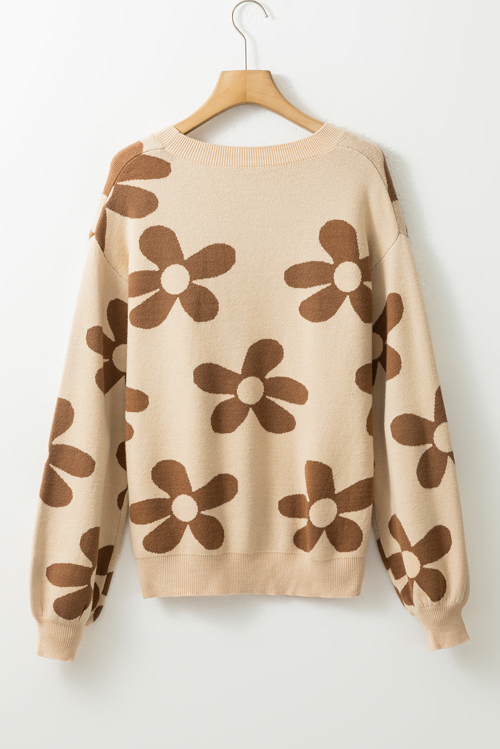 Pergamentfarbener pullover mit großer blume und rippenstrickmuster