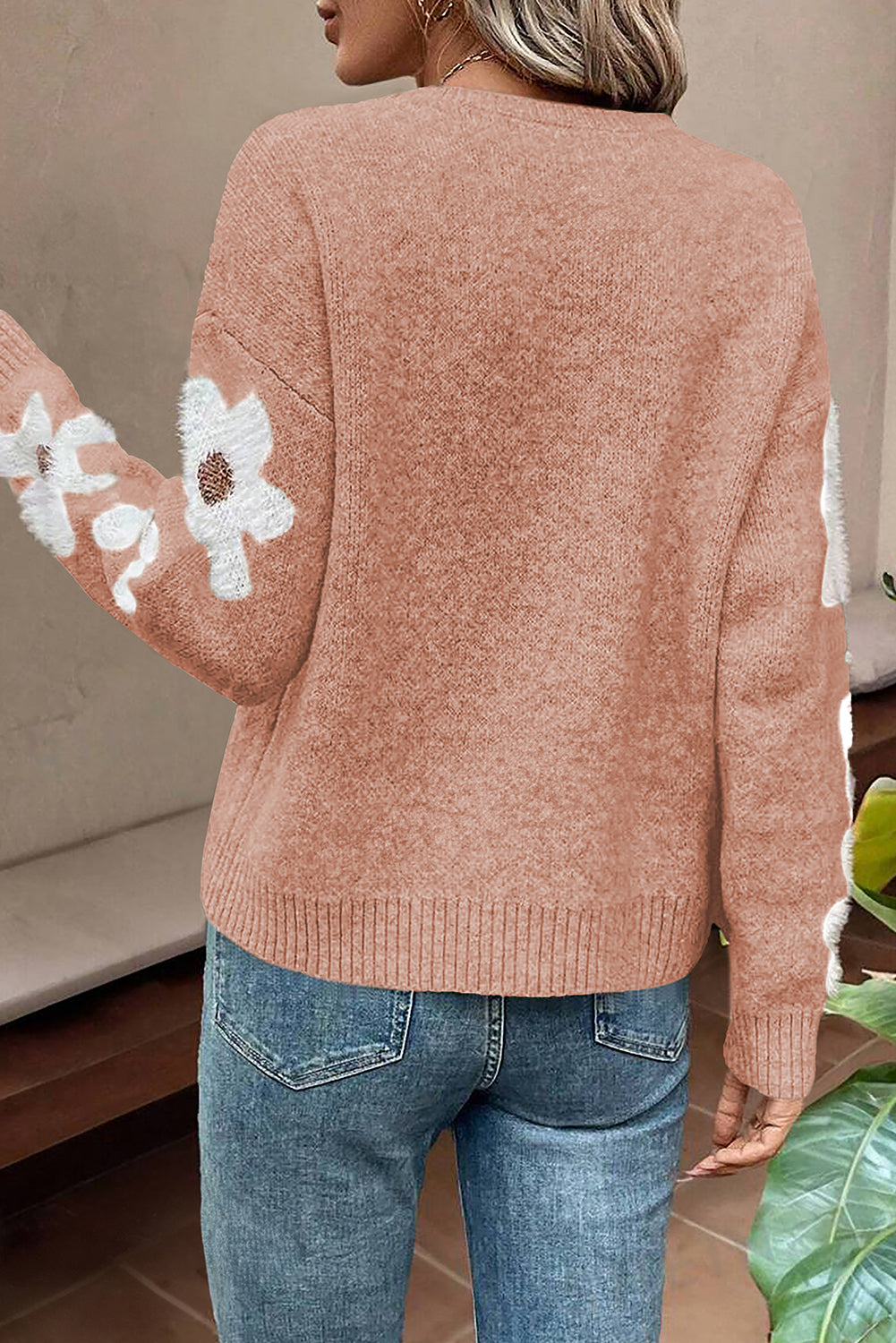 Rosafarbener pullover mit blumenärmeln und hängeschultern