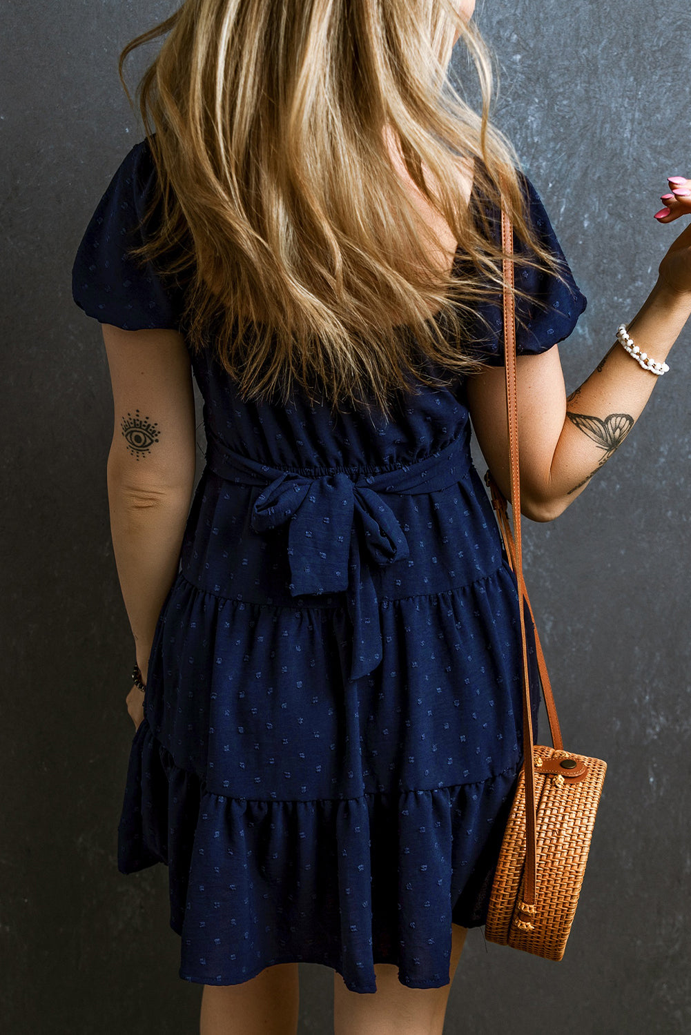 Marineblaues schweizer pünktchen-jacquard-kleid mit puffärmeln und überkreuzten bindebändern