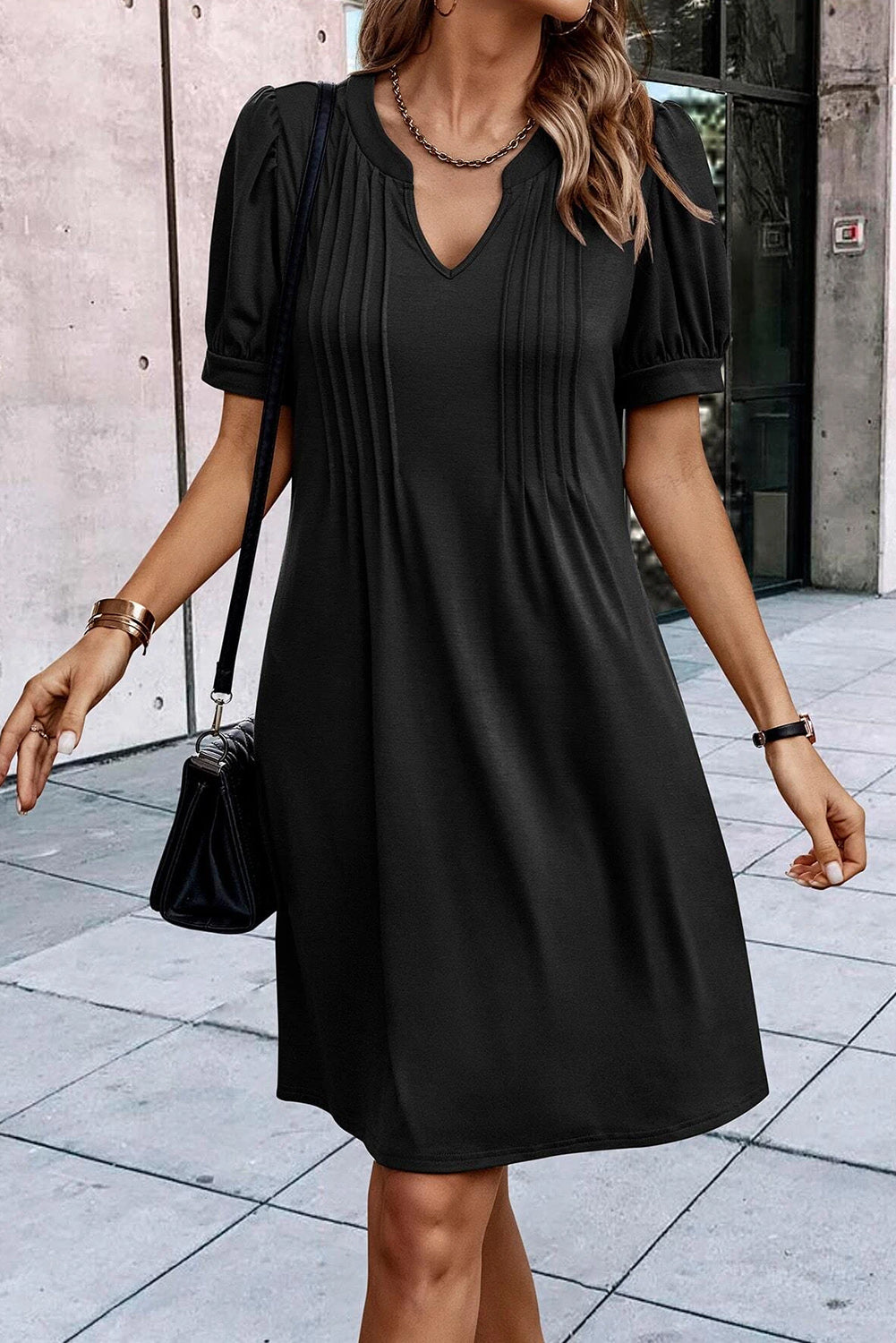 Schwarzes t-shirt-kleid mit plissiertem ausschnitt und puffärmel