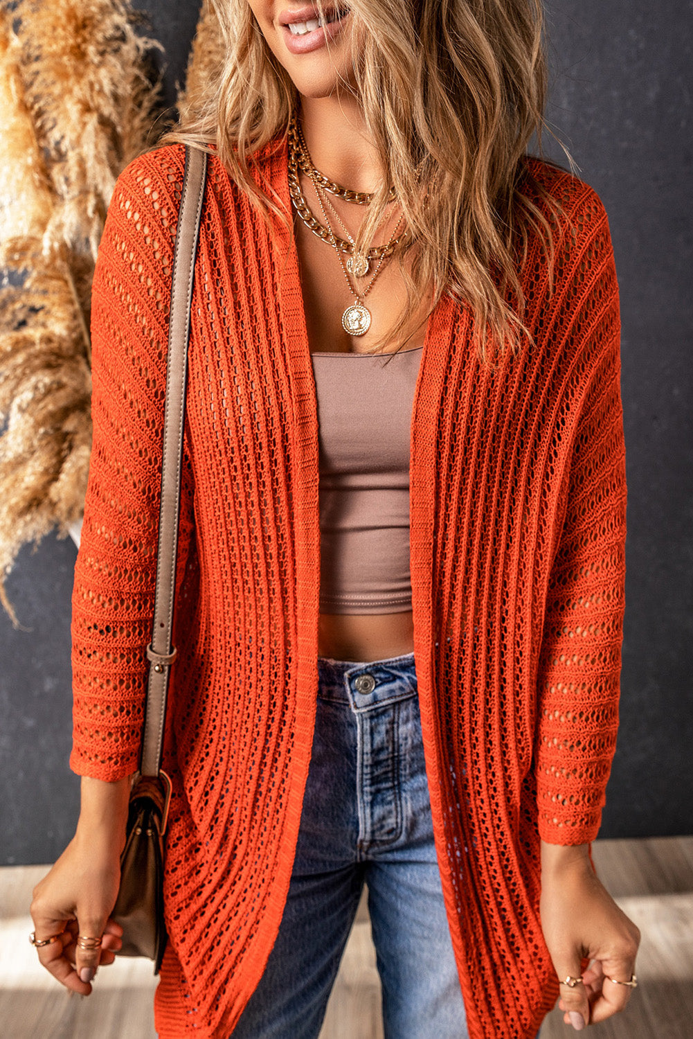 Orangefarbene strickjacke mit ausgehöhlten armbändern an den ärmeln