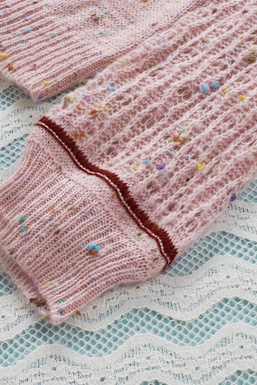 Rosa pullover mit pilling-detail und gemusterten ärmeln