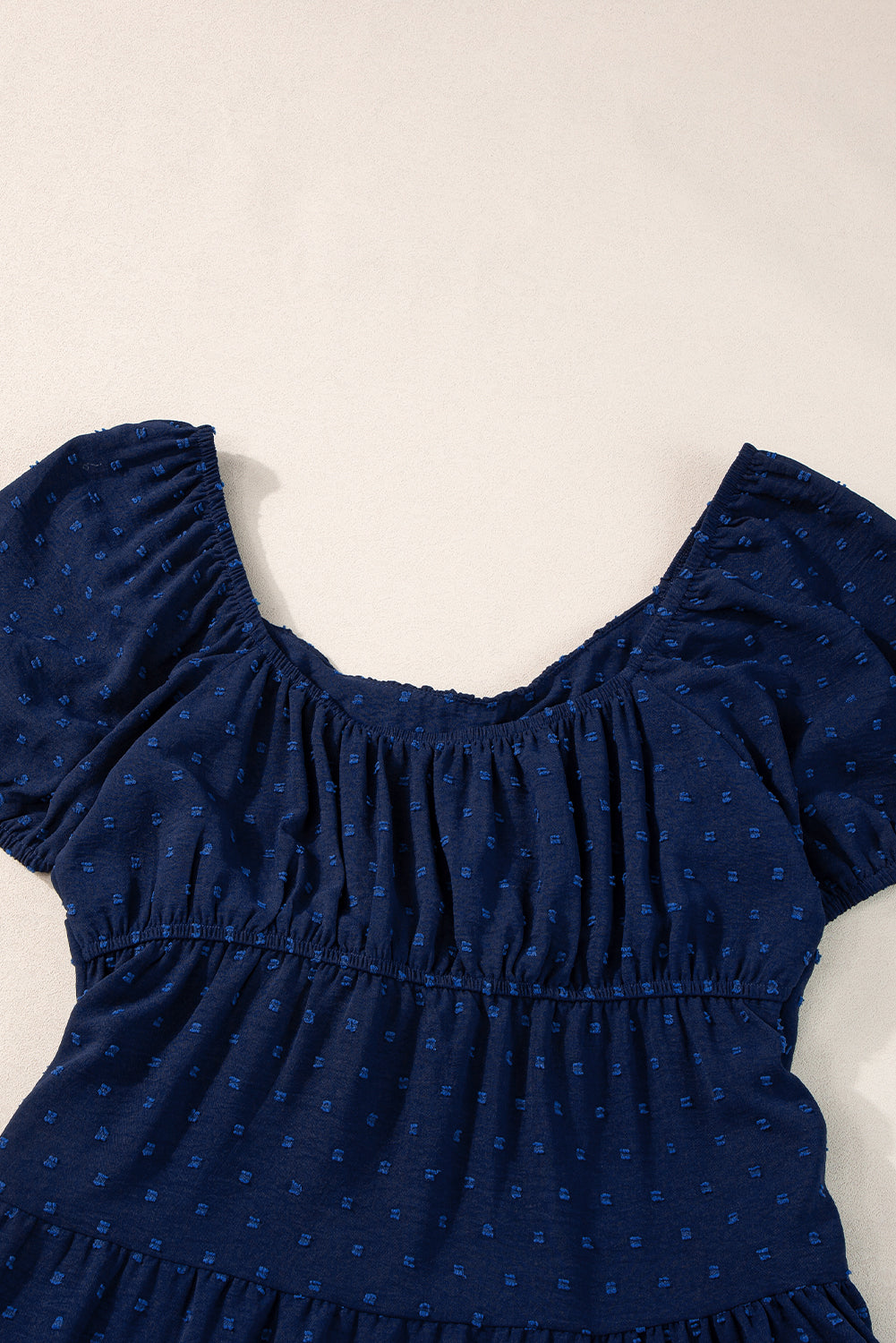 Marineblaues schweizer pünktchen-jacquard-kleid mit puffärmeln und überkreuzten bindebändern